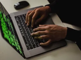 crop cyber spy hacking system while typing on laptop